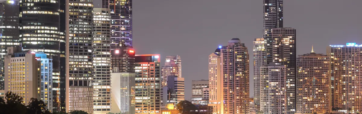 A breathtaking view of Brisbane's illuminated skyline at night with reflections on the river.
