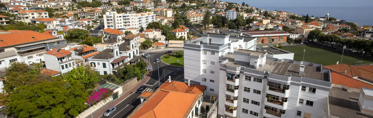 Aerial view of Funchal, Madeira showcasing red rooftops, residential buildings, and the coastline.