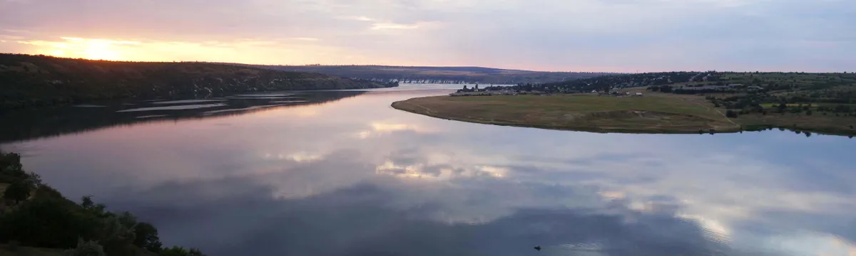 מולדובה: Beautiful sunset reflecting on the Dniester River near Roghi, Moldova, with calm waters and lush surroundings.
