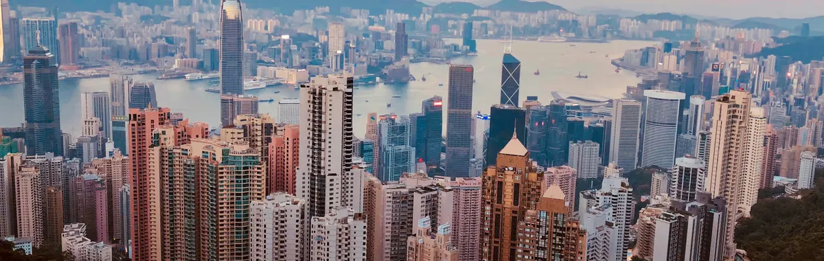 Breathtaking Kowloon skyline with skyscrapers and harbor at sunset, showcasing Hong Kong's urban beauty.