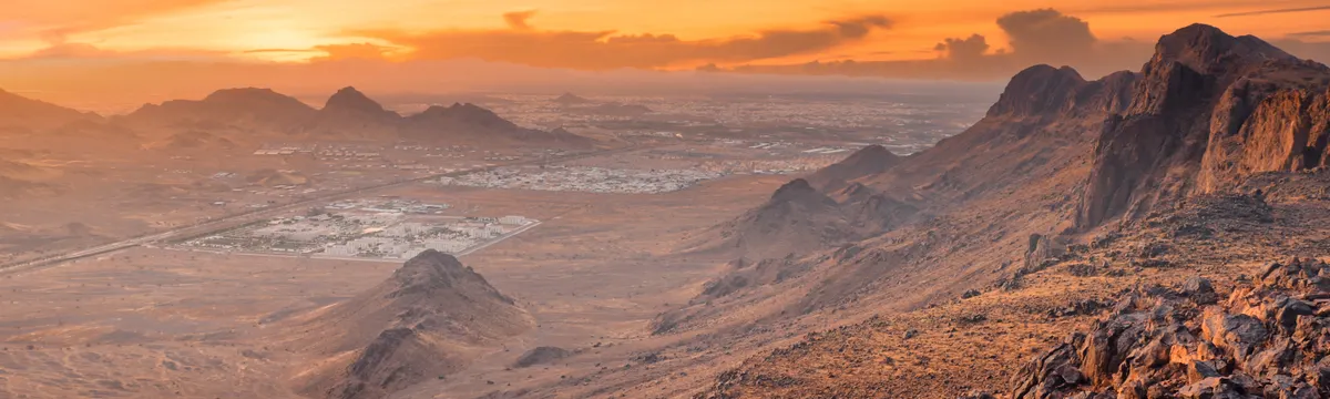 ערב הסעודית: Panoramic view of rocky desert landscape in Medina, Saudi Arabia at sunset, showcasing vibrant sky and mountains.