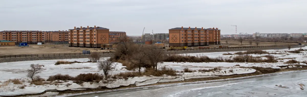 Aerial view of Kyzylorda's residential area with frozen river during winter.