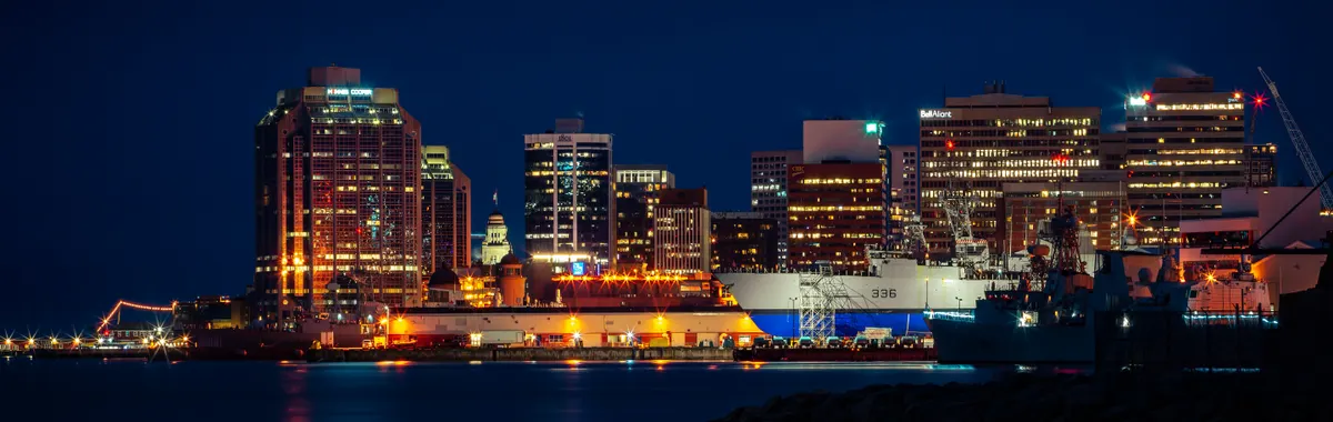Illuminated Halifax skyline along the waterfront, featuring striking city lights reflected in the harbor at night.