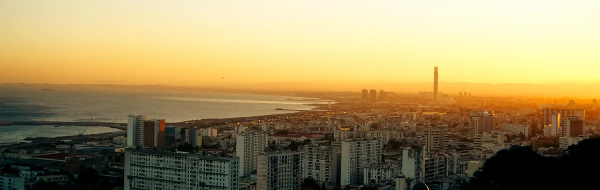 A stunning aerial view of Algiers cityscape at sunrise with a golden sky.