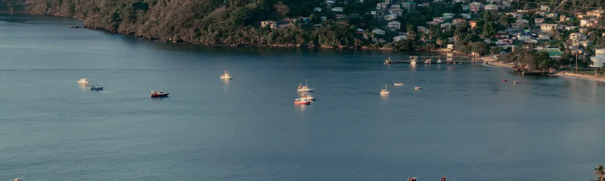 גרנדה: Scenic aerial view of a bay in Grenada with scattered boats and lush hills.