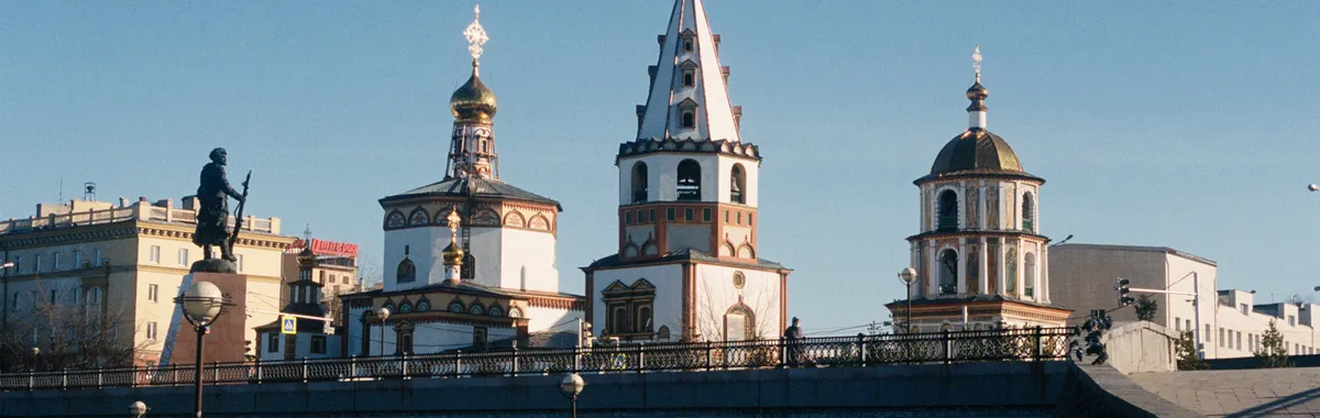 A picturesque view of a historic cathedral facade in Irkutsk, Russia under a clear blue sky.