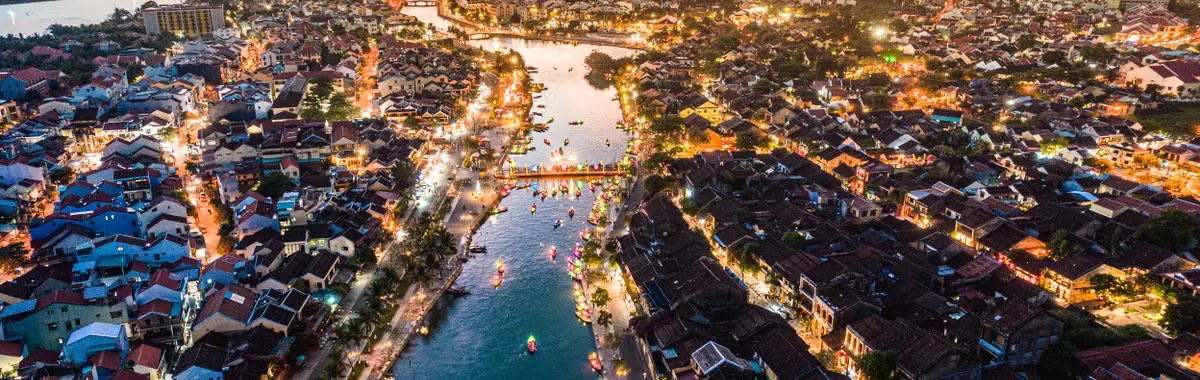 Stunning aerial view of Hội An, Vietnam at sunset. City lights illuminate the historic riverside town.