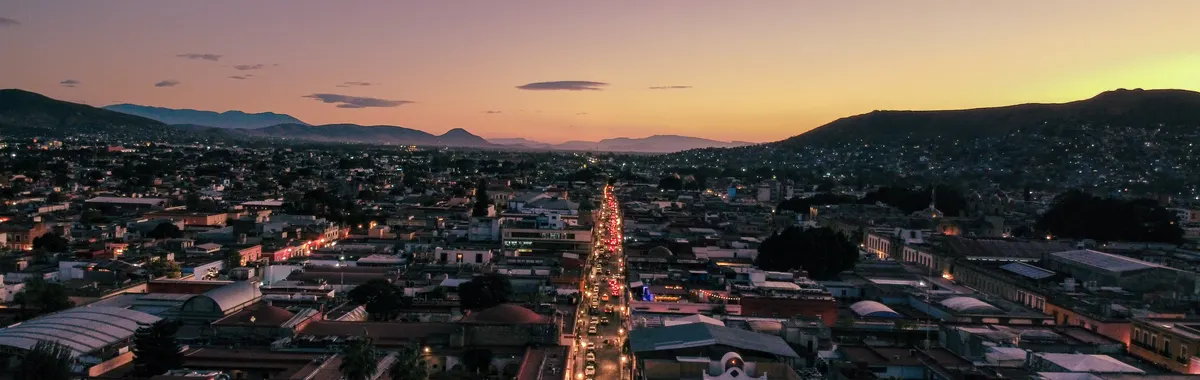 Captivating aerial view of Oaxaca de Juárez at sunset showcasing vibrant city lights and scenic landscape.