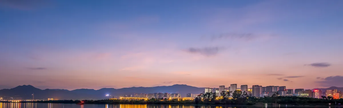Captivating twilight cityscape of Kunming reflecting over calm waters, showcasing serene urban beauty.
