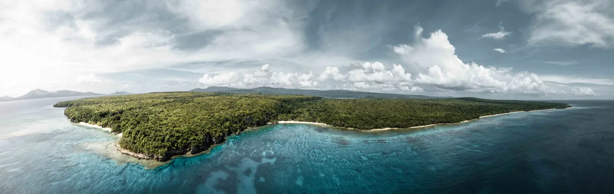 ונואטו: A breathtaking aerial view of the lush green coastline of Vanuatu, surrounded by crystal clear waters.