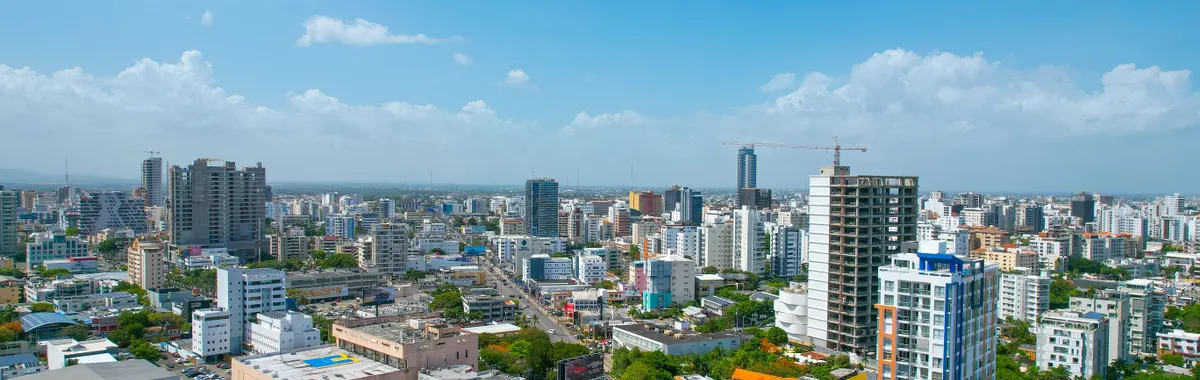 Drone aerial view of Santo Domingo's skyline showcasing urban architecture under a bright blue sky.