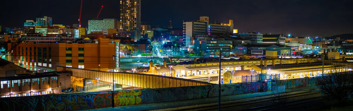 Illuminated night view of Sheffield cityscape showcasing modern architecture and urban life.