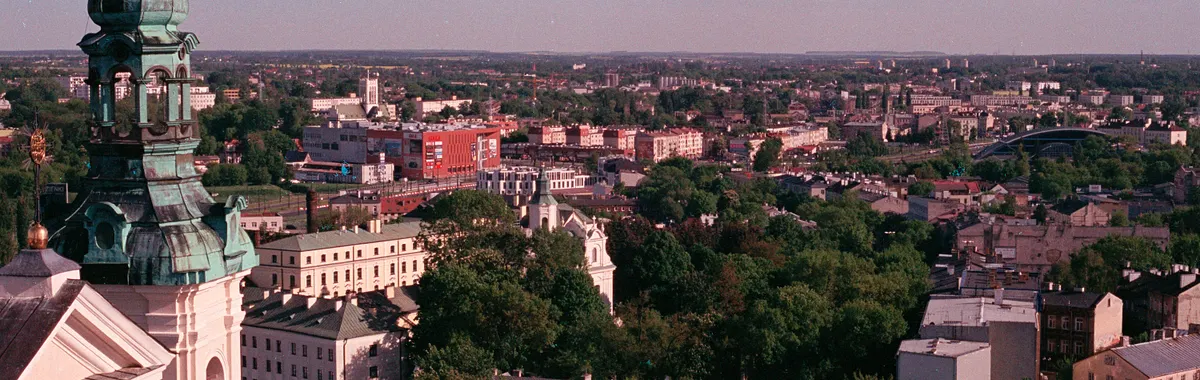 Aerial shot of Lublin, showcasing a historic church and lush greenery among urban buildings.