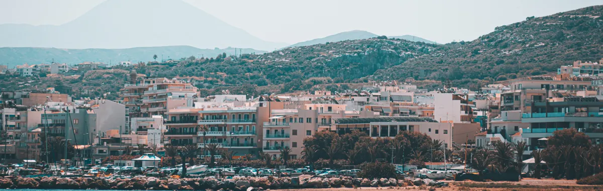 Capture the stunning coastal cityscape of Rethymno, Crete, with mountains and sea.