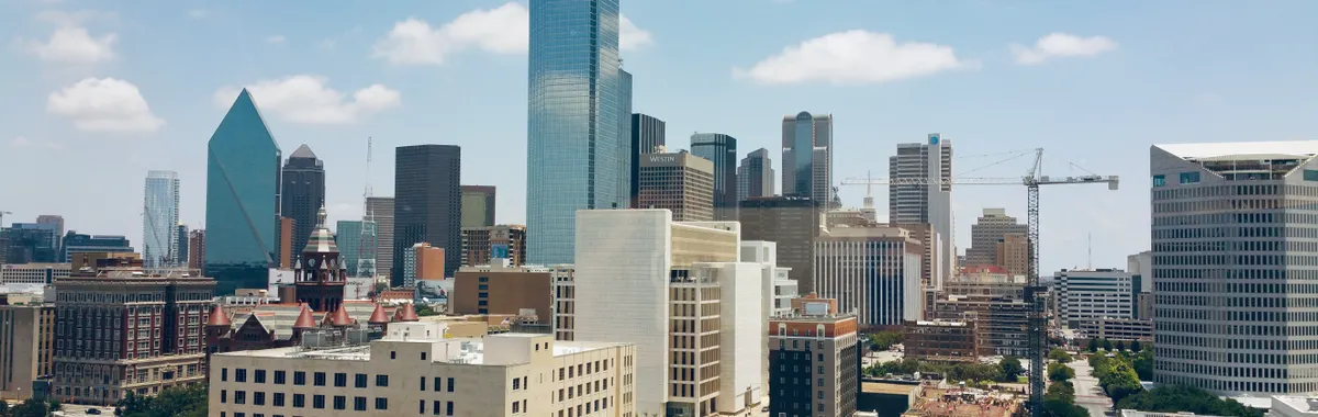 Aerial view of Dallas skyline featuring modern skyscrapers under a clear blue sky.