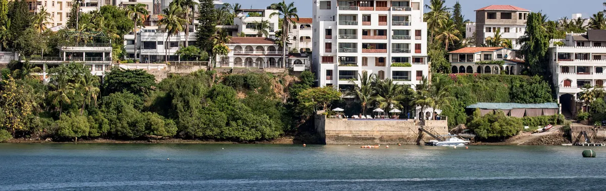 A picturesque view of Mombasa's waterfront featuring buildings and lush greenery.