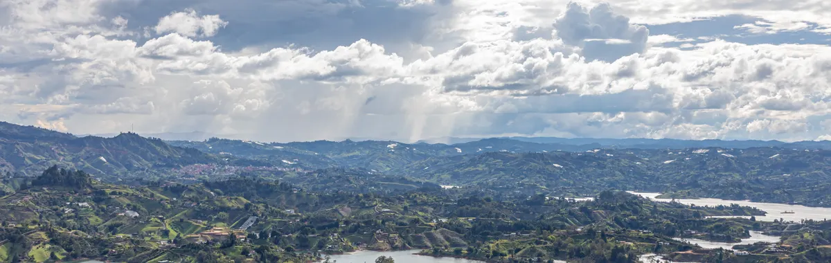 קולומביה: A breathtaking aerial view of the lakes and rolling hills in Guatapé, Antioquia, Colombia, under a dramatic sky.