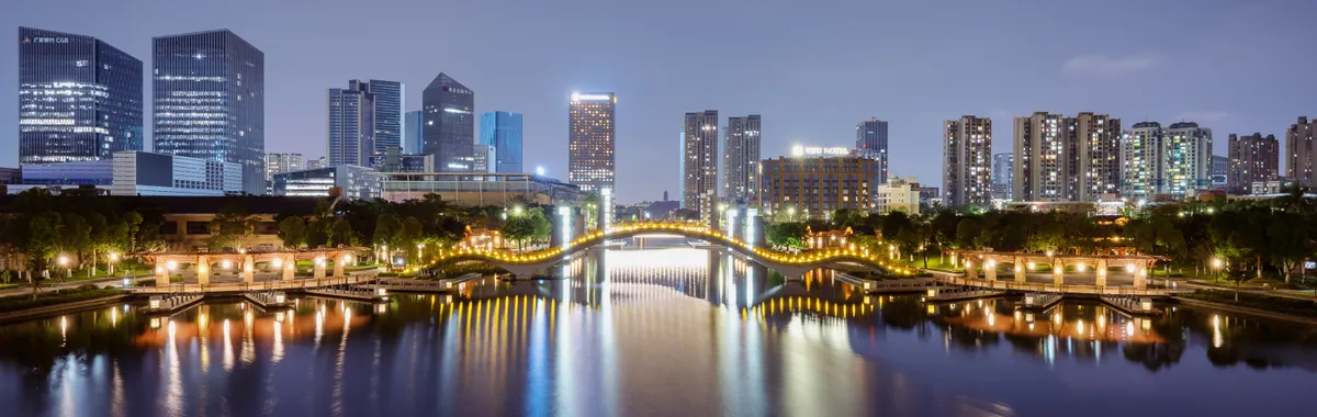 Illuminated skyline and reflections along the river in Foshan, China at night.