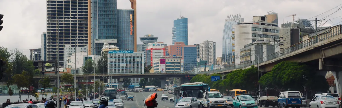 Bikers and cars bustling in Addis Ababa's cityscape with iconic buildings and clear skies.
