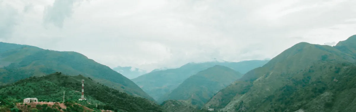 Explore the lush green mountains and valleys of Valledupar, Colombia with misty skies.