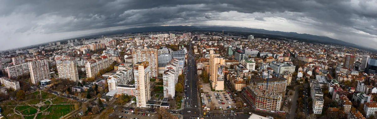 Dramatic aerial view of Sofia, Bulgaria showcasing urban architecture beneath cloudy skies.