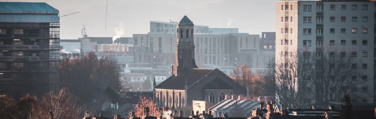 Urban view of Bristol featuring St Luke's Church amidst city buildings during a serene sunset.