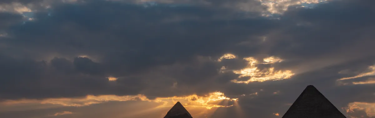 The Pyramids of Giza during a stunning golden hour sunset, capturing iconic silhouettes.