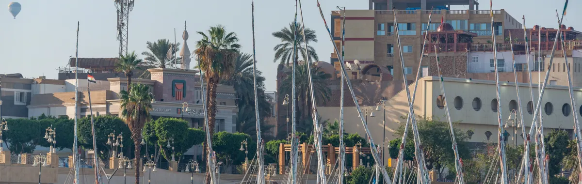 Sailboats moored in Luxor's marina against historic architecture.