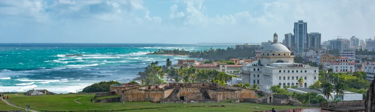 פוארטו ריקו: Explore the stunning view of San Juan's historic fort with ocean backdrop under a vibrant sky.