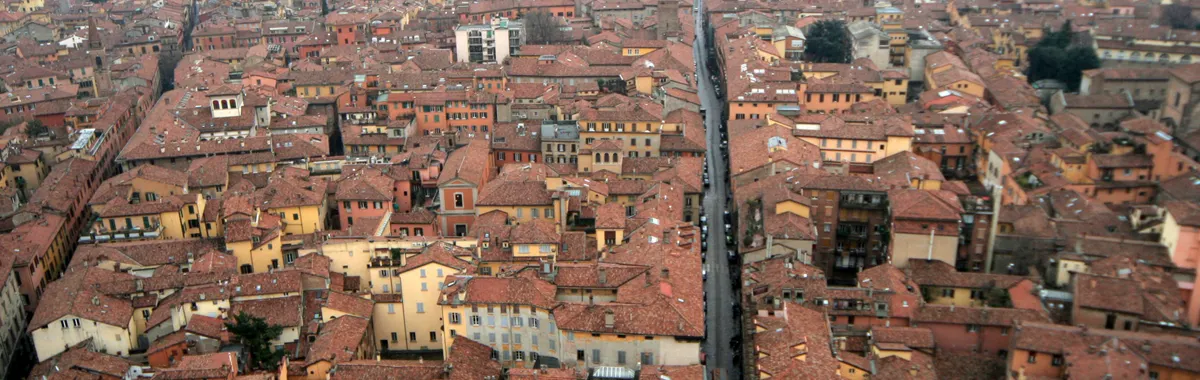 Aerial shot of Bologna, Italy showcasing its historic red rooftops and medieval architecture.