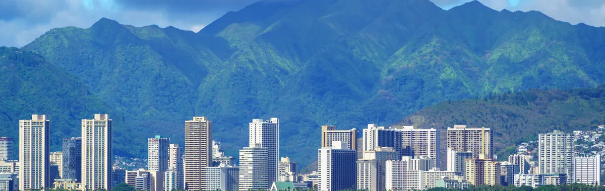 Stunning aerial view of Honolulu's skyline with lush mountains and ocean in foreground.