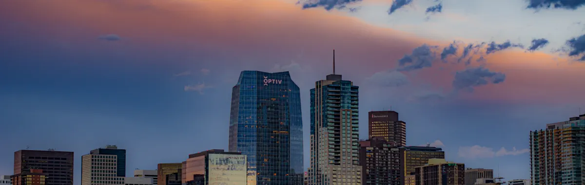 Stunning view of Denver's cityscape with skyscrapers under a colorful sunset sky.
