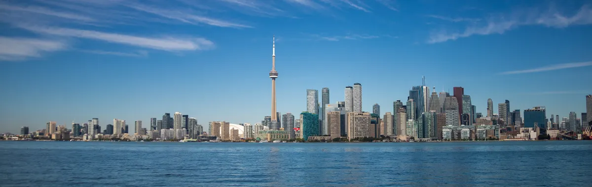 Scenic view of Toronto city skyline featuring the CN Tower and waterfront under a clear blue sky.