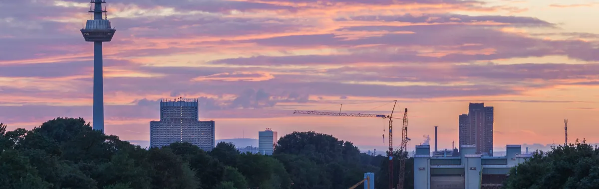 Colorful sunset over Mannheim skyline featuring the iconic Fernmeldeturm tower and urban landscape.