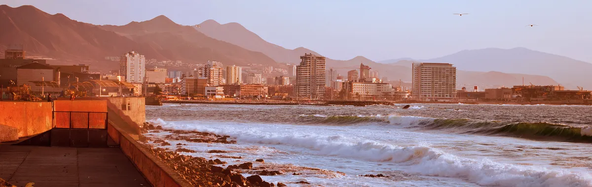 Stunning sunset over Antofagasta coastline, featuring urban landscape and rocky beach.