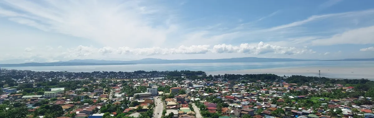 Aerial view of Davao City with a vast coastline and scenic Samal Island in the background.