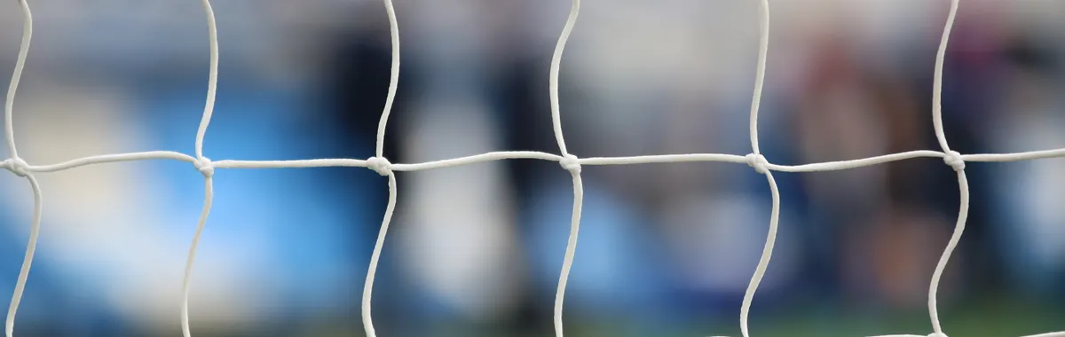 Close-up view of a soccer net with a blurred background of a sports field in Saint-Denis, France.