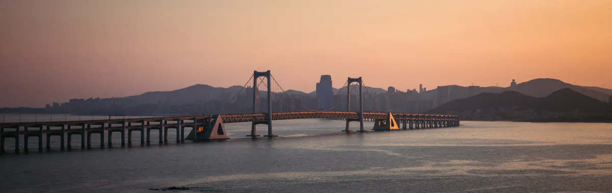 Explore the scenic beauty of Dalian's Xinghai Bay Bridge bathed in sunset light.