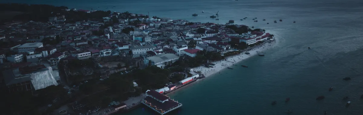 A stunning aerial view of Zanzibar's coastline at twilight, showcasing the city's architecture and ocean.