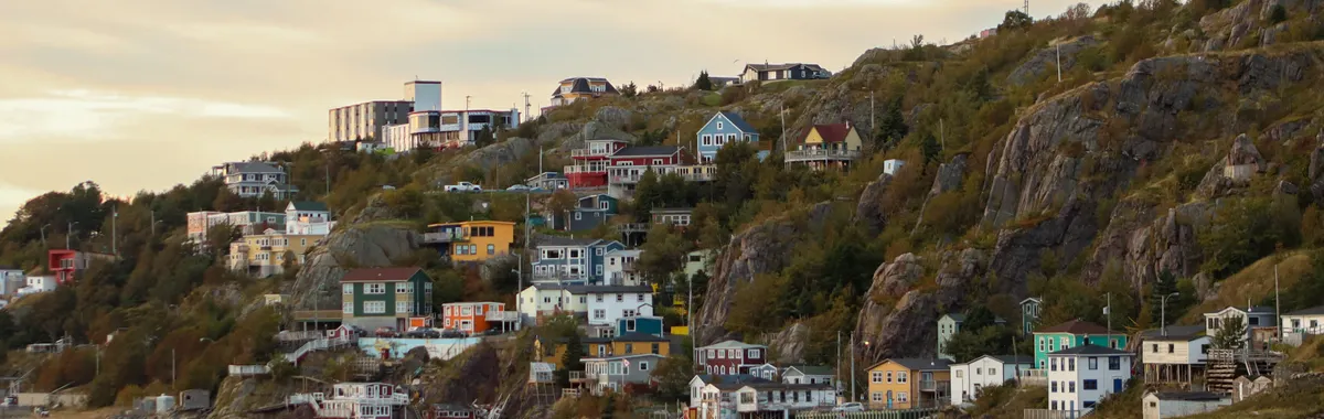 Charming multicolored coastal houses in St. John's overlooking the ocean during twilight.