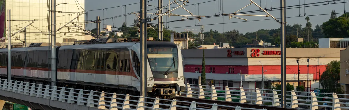 A train traveling on an elevated track in the urban landscape of Zapopan, Mexico.