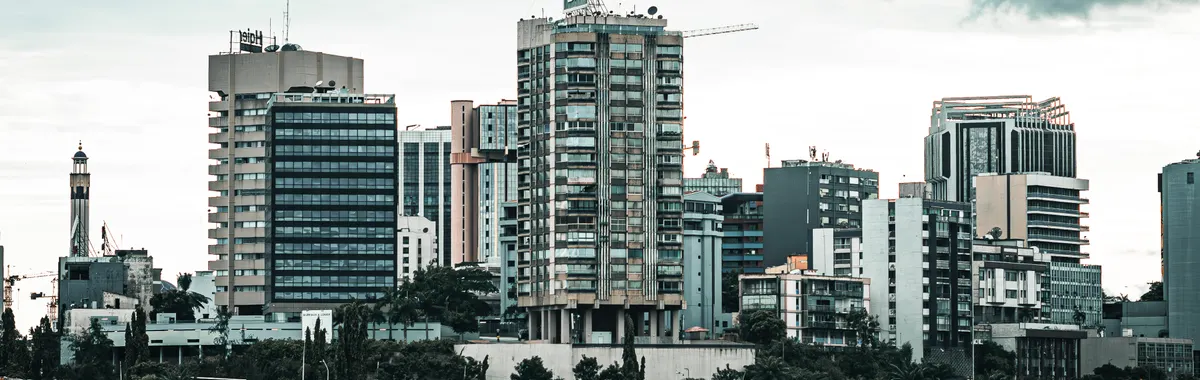 Contemporary cityscape of Abidjan featuring high-rise buildings by the waterfront under overcast skies.