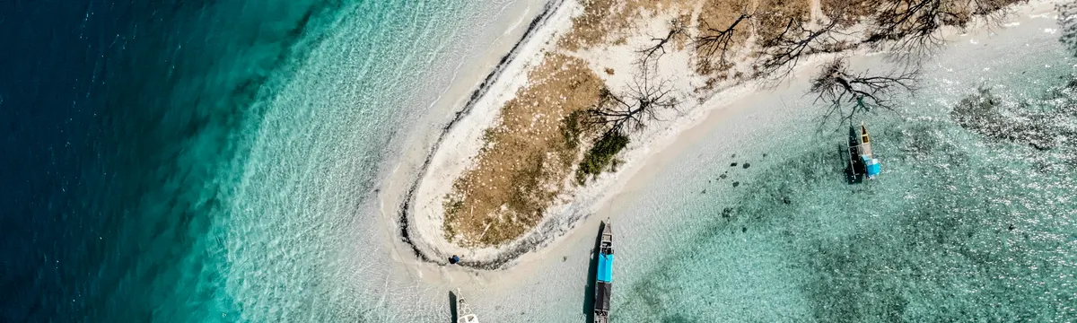 קומורו: A stunning aerial view of Comoros island coastline with boats in turquoise waters.
