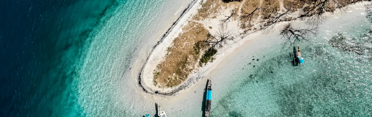 קומורו: A stunning aerial view of Comoros island coastline with boats in turquoise waters.