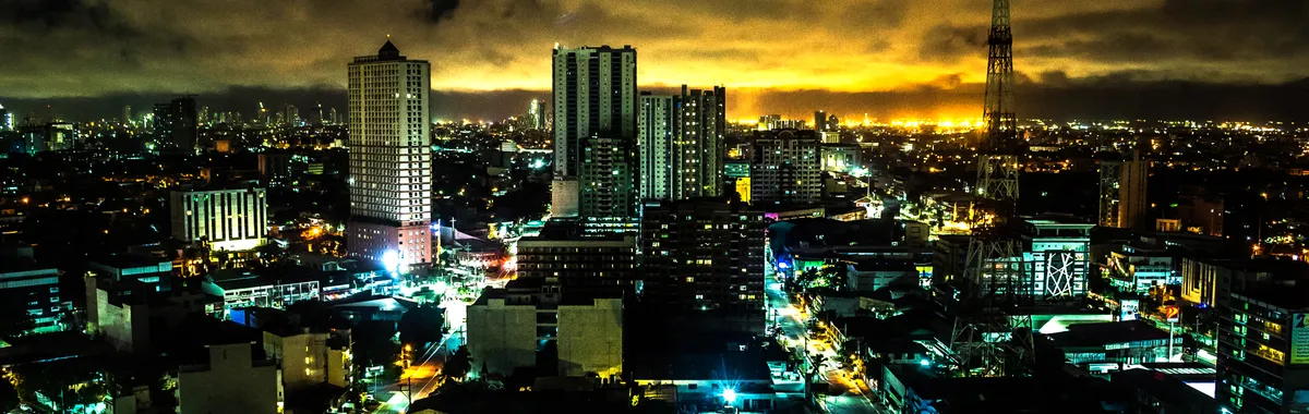 Stunning night view of Quezon City skyline with illuminated buildings and vibrant city lights.