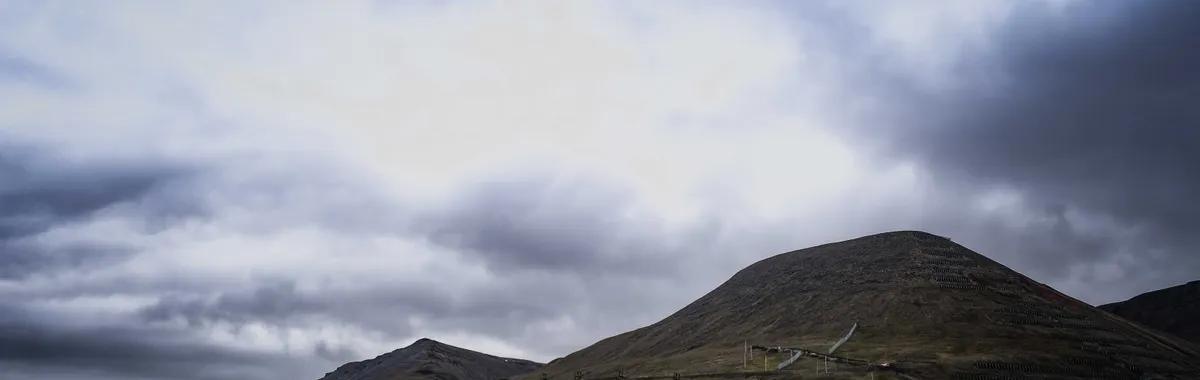 A picturesque view of Longyearbyen, Svalbard, with colorful houses and mountains under dramatic clouds.