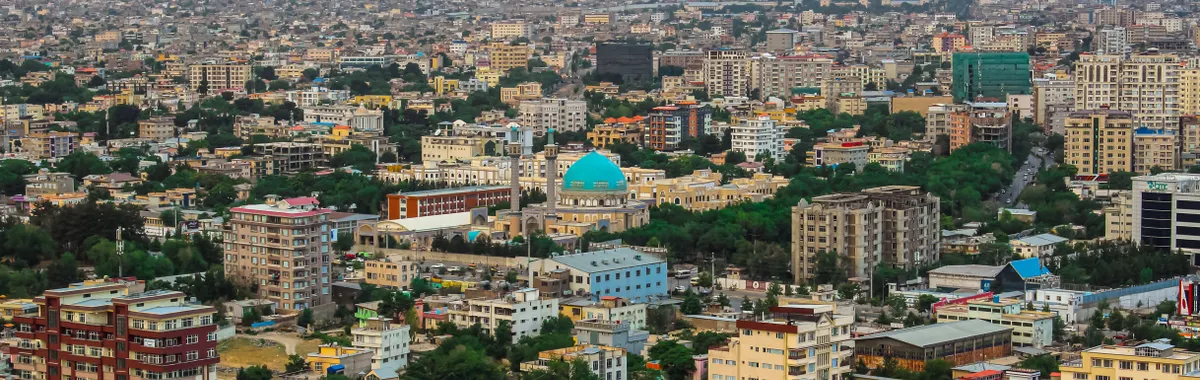 Aerial cityscape of Kabul featuring a prominent mosque amidst modern architecture and mountains.