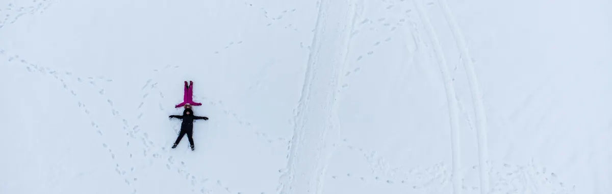 Aerial shot of two people making snow angels on a snowy field in Tolyatti, Russia.