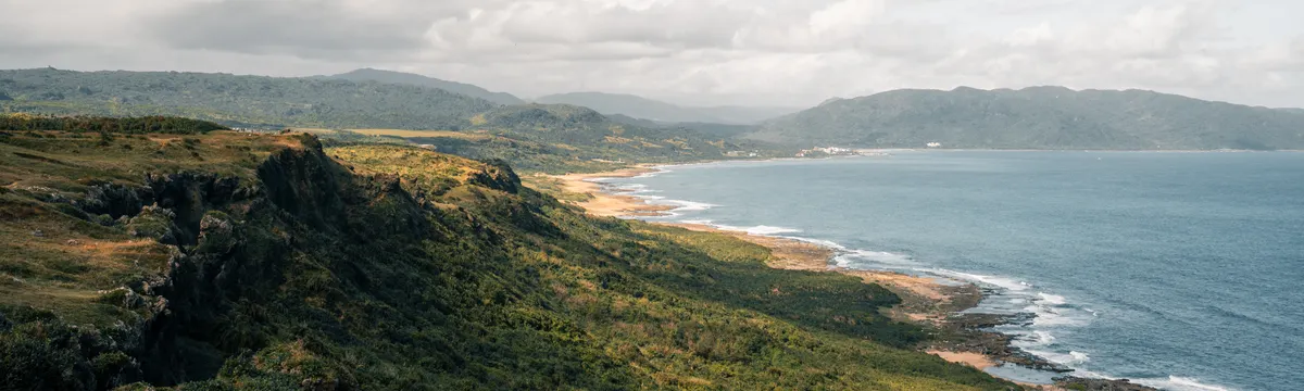 טייוואן: A breathtaking aerial view of lush greenery and ocean along Taiwan's coastline.