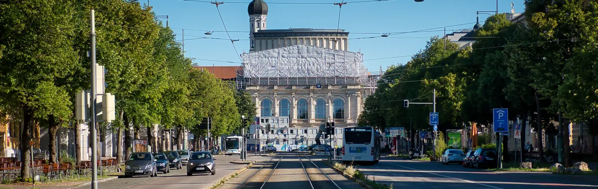 A scenic view of a historic building and tram tracks in Augsburg, Germany, under clear blue skies.